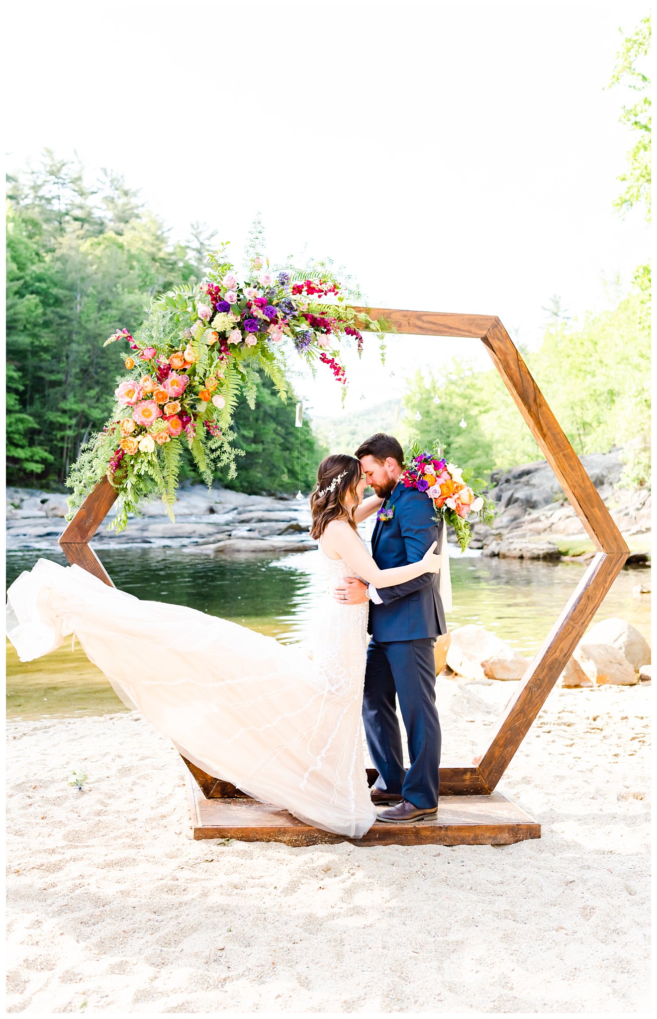 Bride and groom under floral arch at creekside wedding