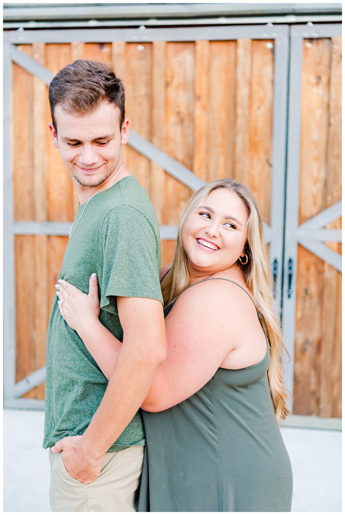 couple posing in front of barn doors for summer engagement session
