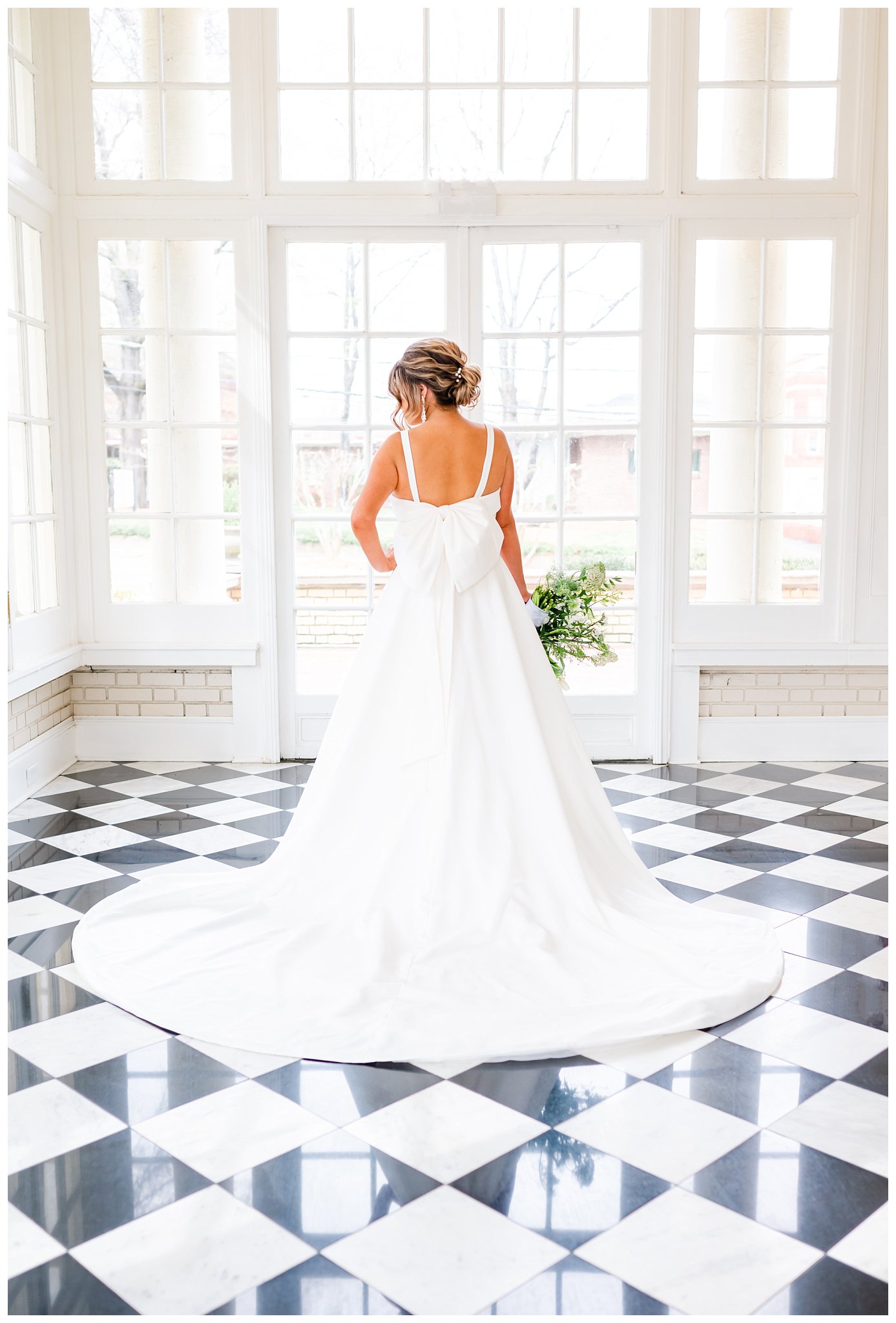 back of bride's dress with large bow standing on black and white tile floor