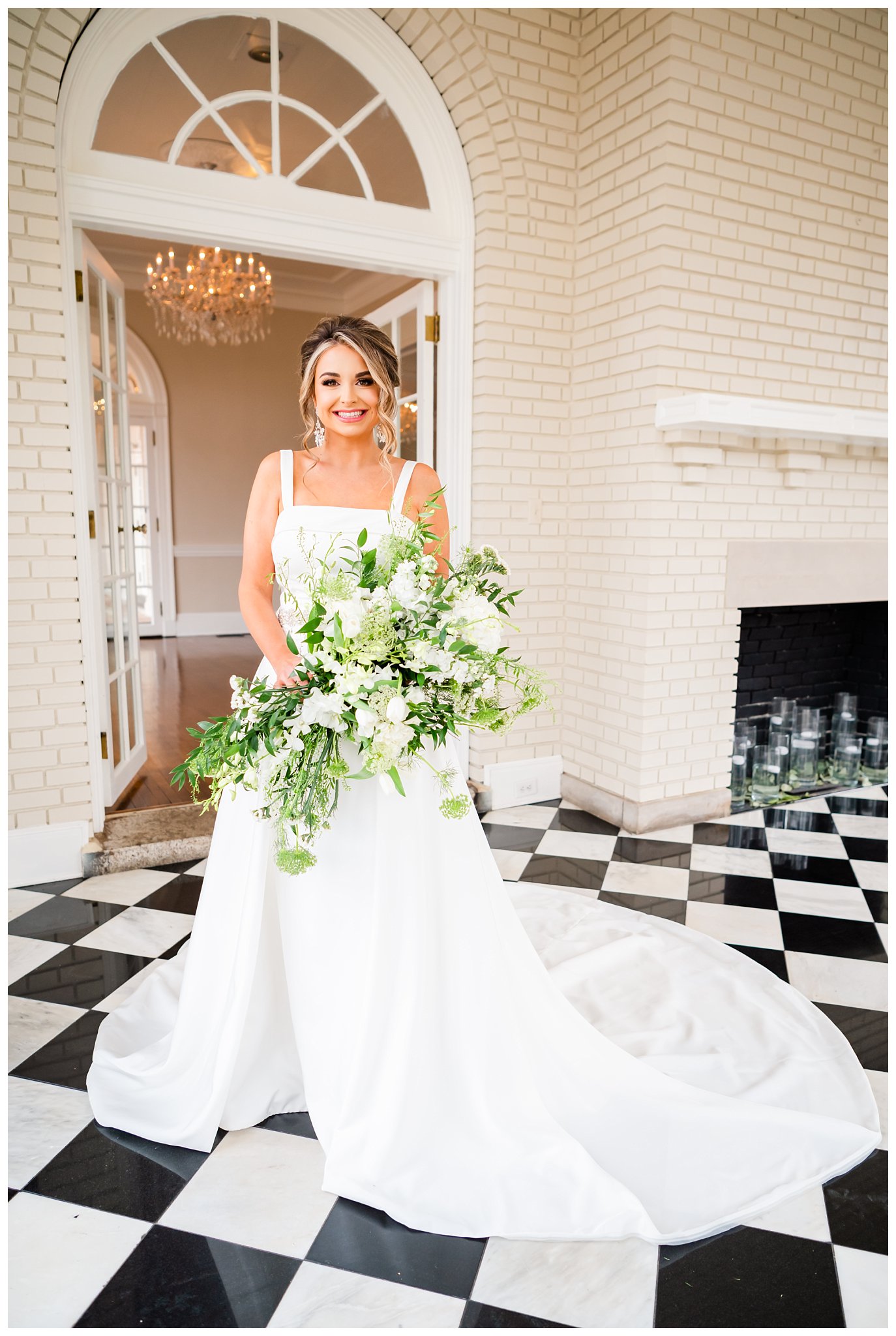 bride at mansion holding large green and white bouquet