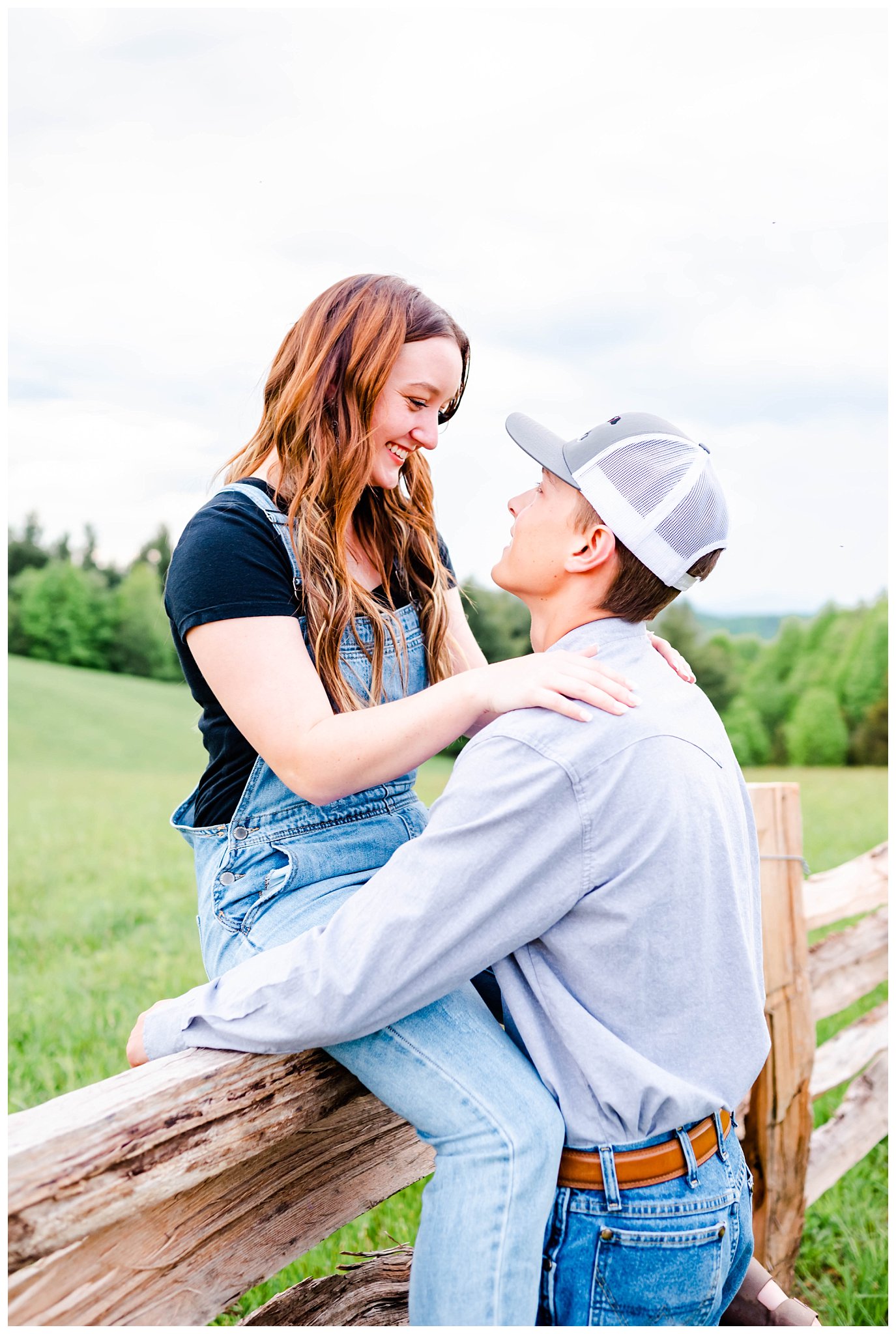 couple posing on wooden fence for mountain top engagement