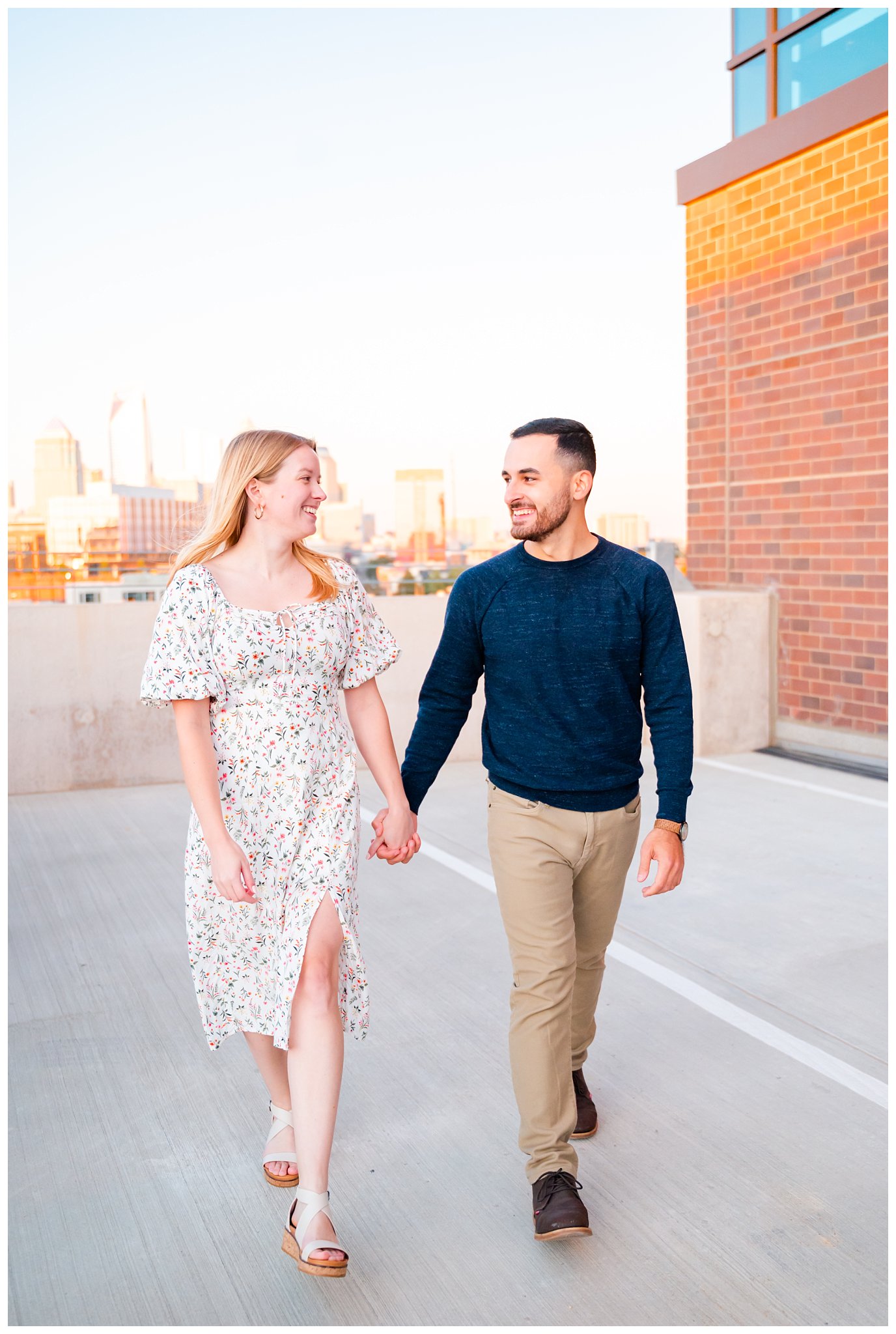 couple holds hands on rooftop for their downtown Charlotte engagement session