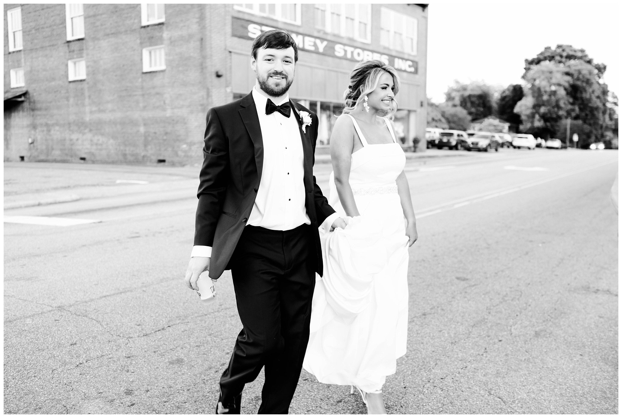 black and white photo of bride and groom walking in downtown Fallston, NC for their North Carolina summer wedding